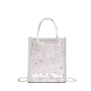 Transparent PVC tote bag with white daisy print, top handle and gold chain strap