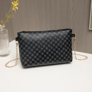 Elegant black crossbody chain bag with floral pattern on a minimalist wooden background