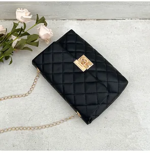 Close-up of black quilted shoulder bag with golden chain strap and metal lock detail