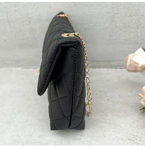 Side view of black quilted crossbody bag showing thick structure and gold chain strap