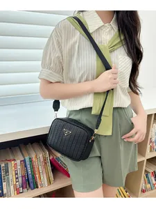 Close-up of woven texture crossbody bag with gold metal plate and nylon strap