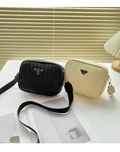 Detail of woven texture crossbody camera bags with triangular metal logo in black and cream