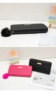 Détail du portefeuille matelassé avec plaque dorée, fermeture éclair et pompon en peluche