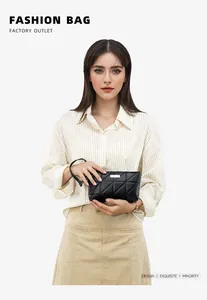 Detail of black quilted leather hand bag with gold metal logo and wrist strap