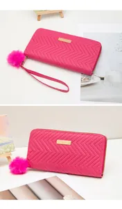 Détail du portefeuille zippé rose rouge avec coutures en V et pompon duveteux assorti