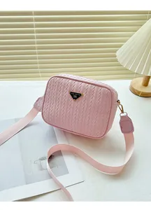 Detail of pink woven texture crossbody camera bag with metal logo and wide strap