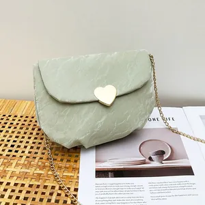 Mini sac selle vert texture marbre avec fermoir cœur doré et bandoulière chaîne sur tapis