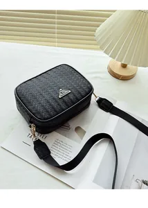 Detail of the black woven texture and golden metal triangle logo on the camera bag