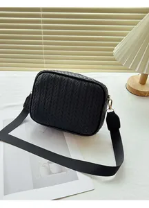 Detailed close-up of a black woven leather camera bag with golden metal buckles