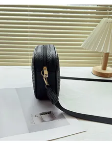Detailed view of black woven texture camera bag with gold zipper and fabric strap
