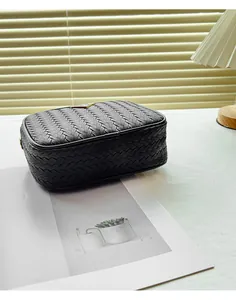 Close-up of black woven leather camera bag with golden triangle logo in a lifestyle setting