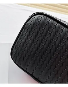 Close-up of the black intrecciato woven pattern and curved edge of this crossbody camera bag