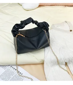 Detail of black lychee grain pillow bag with pleated handle and gold chain strap