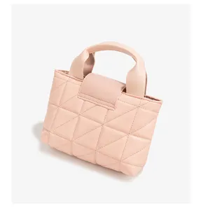Detailweergave van lichtroze gewatteerde handtas met elegante driehoekige stikselstructuur