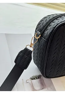 Detail of black woven camera bag featuring gold lobster clasp and nylon shoulder strap
