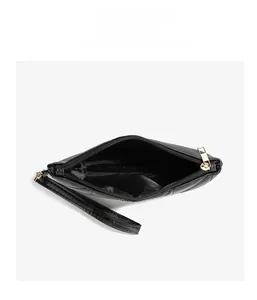Close-up of black quilted zipper clutch with golden hardware and hand wrist strap