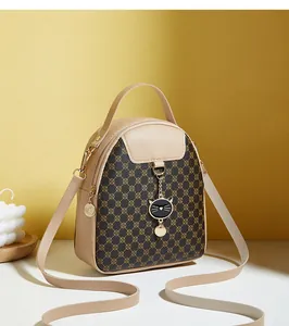 Detalle de mini mochila multifuncional con colgante de gato y estampado floral marrón