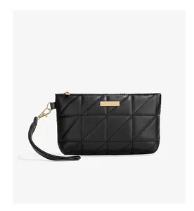 Detail of black quilted leather wristlet bag with triangle stitching and gold metal plate