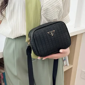 Black woven leather camera bag with golden triangle plaque and wide fabric shoulder strap