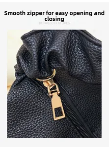 Macro view of smooth golden zipper and premium litchi grain leather texture on black bag