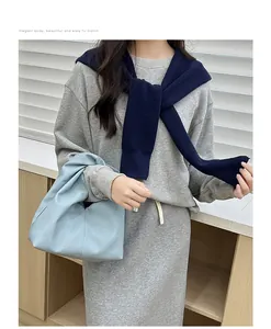 Close-up of elegant light blue pebble leather cloud bag matched with casual knit outfit