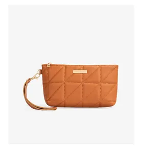 Detail of caramel quilted leather phone bag with gold metal plate and wrist strap