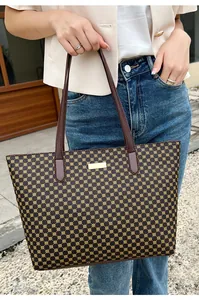 Close-up of a large tote bag with yellow geometric prints and brown leather handles