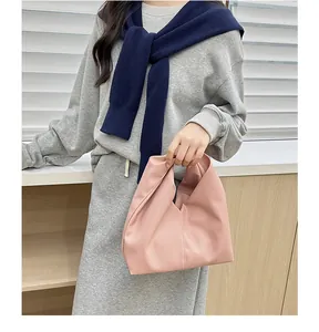 Pink cloud handbag featuring soft pleats and wide handle shown with a stylish outfit