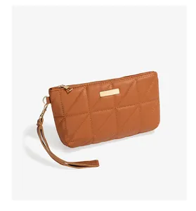 Detail shot of brown quilted faux leather clutch bag with golden metal hardware and strap