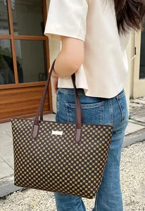 Outdoor shot of a large brown floral tote bag with leather straps and gold metal plate