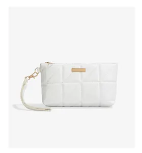 Detail of white quilted handbag featuring triangular embroidery and gold hardware accents