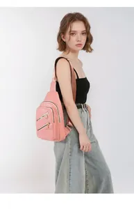 Side view of a pink faux leather crossbody chest bag on a model with adjustable strap