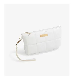 Detail of white quilted handbag featuring triangle stitching and gold metal plate
