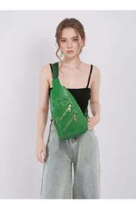 Detail of emerald green lychee leather chest bag with three golden metal zippers