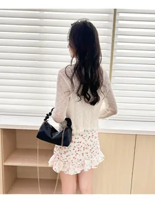 Rear view of model holding black lychee pattern leather bag with gold chain strap