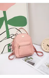 Close-up of pink mini backpack with V-quilted faux leather and white butterfly buckle