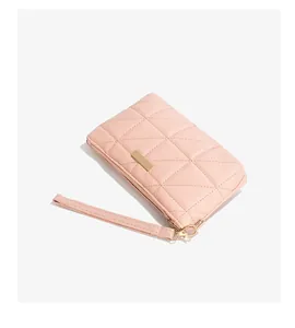 Close-up of pink quilted ladies wristlet bag with geometric triangle stitching and metal plate