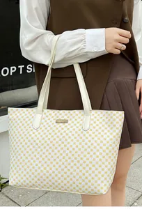 Detail of large tote bag with yellow geometric pattern and white leather handles