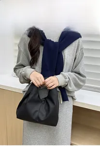 Close-up of black lychee texture handbag on model with minimalist pleated cloud bag style