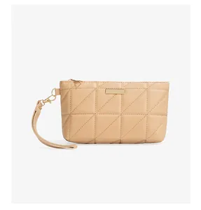 Detail of beige quilted mini bag with triangle stitching and gold metal brand plate