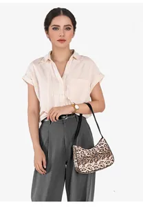 Gros plan du sac croissant imprimé léopard avec bandoulière noire porté en mode décontracté