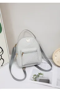 Detail of grey mini backpack with chevron quilting and golden butterfly metal hardware