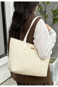 Detail of yellow geometric pattern tote bag with slim white straps and metal plate
