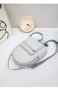 Detail of light gray quilted PU leather mini backpack with golden butterfly ornament