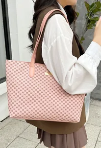 Pink geometric pattern tote bag detail with slender shoulder straps and gold metal plate