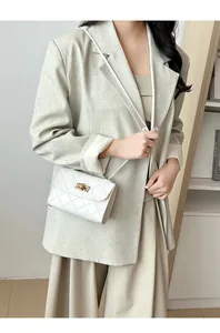 Close-up van witte gewatteerde crossbodytas met gouden draaisluiting getoond op model