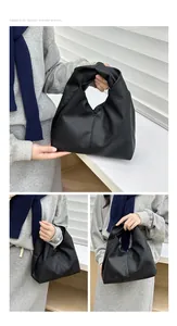 Detail of black lychee texture handbag with unique knotted handle and triangular structure
