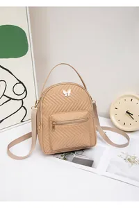 Detail of a khaki quilted backpack with a white butterfly metal buckle and adjustable straps