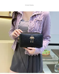Close-up of quilted crossbody bag with golden swan ornament on purple knitwear