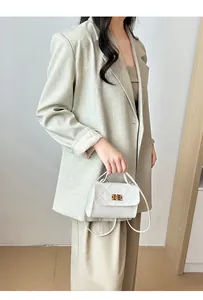 Detailopname van een witte gewatteerde crossbodytas gecombineerd met een groene blazer